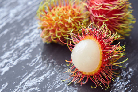Three Rambutan on a wet slate cutting boardの写真素材