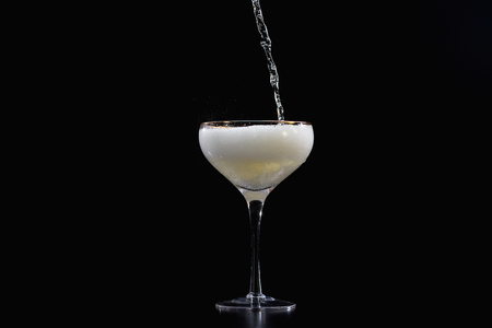 Pouring Champagne sparkling wine into glass with splashの写真素材
