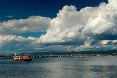 boat on the sea ant turquoise sky with cream cloudsの写真素材