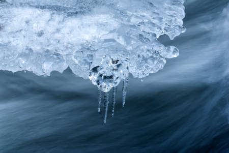 Fluent water and icicles in mountain river