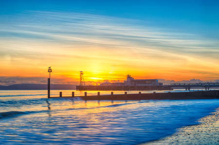 The lights of Bournemouth Pier at night reflected in the wet sand on the beach. Dorset England UK Europe.の写真素材