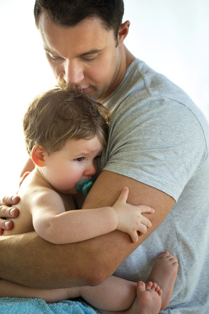 Baby boy being comforted by his fatherの写真素材