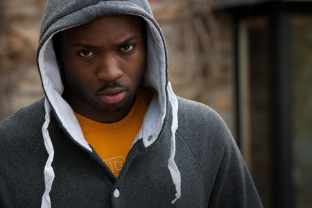 Young man with his hood up looking angrily at the camera