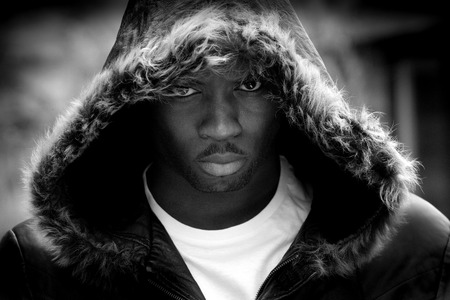 Young man with his hood up looking angrily at the camera