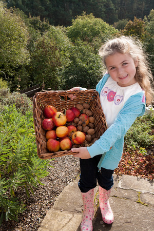 Young girl posing with a basket of hand-picked fruitの写真素材