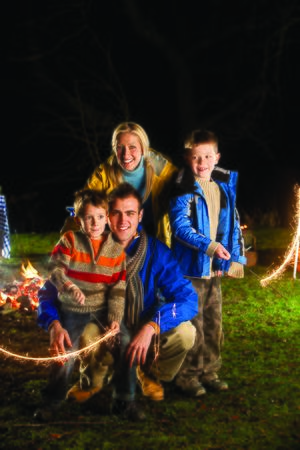 Brothers posing with sparklers on bonfire night with their parentsの写真素材