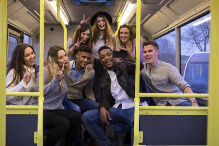 Group of young adults taking a selfie at the back of a bus.の写真素材