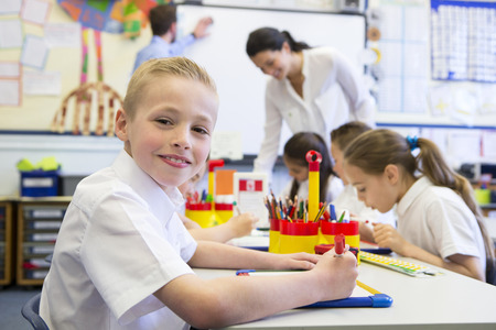 Portrait of a cute young schoolboy smiling at the camera while sitting at his desk.