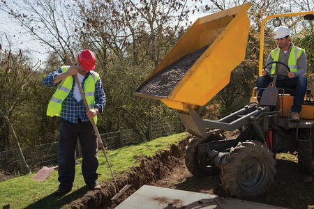 Two male construction workers using heavy machineryの写真素材