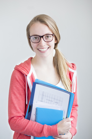 Portrait of an attractive young girl on a white background. She is holding folders and paper work.の写真素材