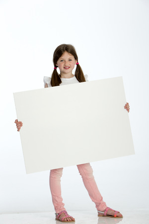 Little girl holding a blank sign against a white backgroundの写真素材
