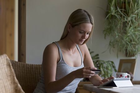Woman using her digital tablet in her home to make an online card payment.の写真素材