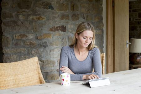 Woman sitting in her home using a digital tabletの写真素材