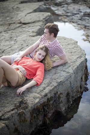 Beautiful couple lying on the rocks at the beach.の写真素材