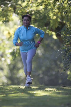 Woman running across a field on a cold morningの写真素材