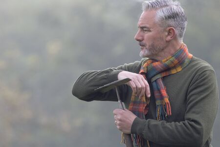Man with a rake looking into the fog on a field.の写真素材
