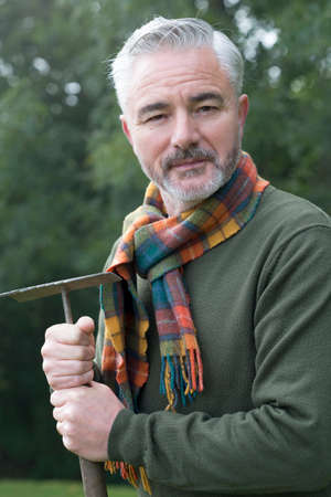 Portrait of a man holding a rake whilst working outdoorsの写真素材