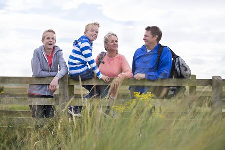 Happy Family of Four on a bridge. They are wearing casual clothing and looking at the surrounding...