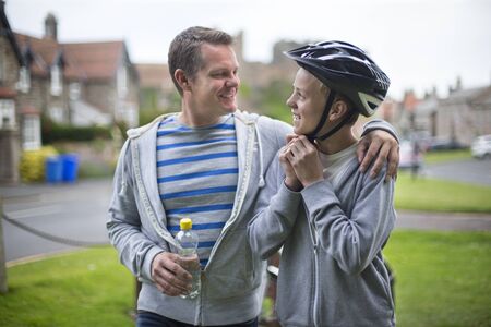 Father and Son getting ready for their bike ride. The father has his arm around his son and they are...