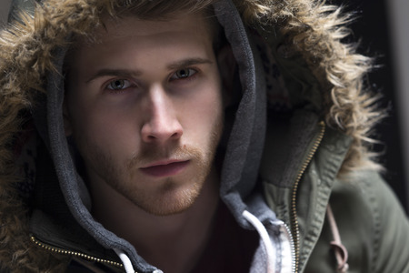 Close up portrait of a young man posing with his hood up.の写真素材