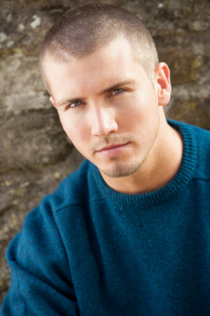 Attractive young man sitting outside. He is looking pensively at the camera.の写真素材