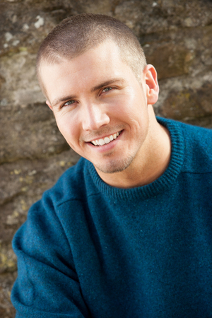 Attractive young man sitting outside. He is smiling at the camera.の写真素材