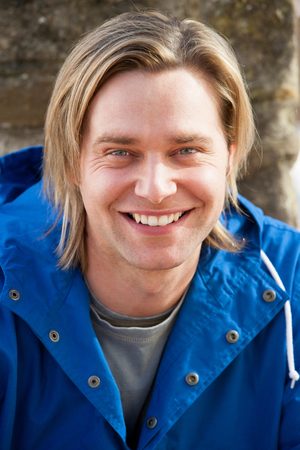 Attractive young man sitting outside. He is smiling at the camera.の写真素材