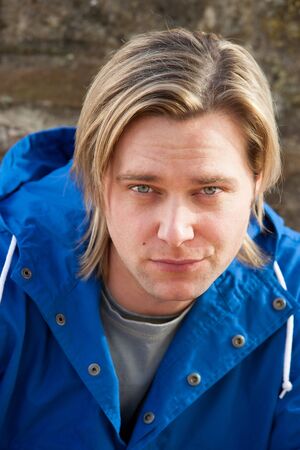 Attractive young man sitting outside. He is looking pensively at the camera.の写真素材