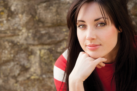 Close up portrait of an attractive young woman sitting outside smiling for the cameraの写真素材