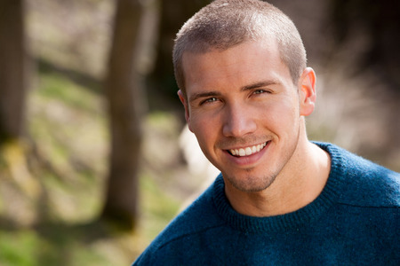Attractive young man sitting outside. He is smiling at the camera.の写真素材