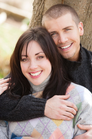 Attractive young couple cuddling out doors. They are both looking at the cameraの写真素材