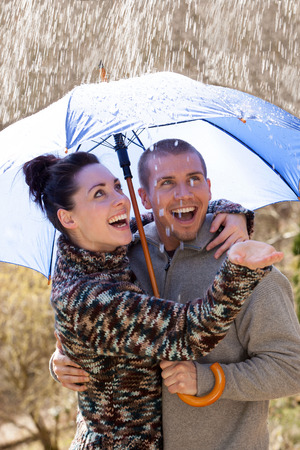 Young couple enjoying the rain under an umbrellaの写真素材