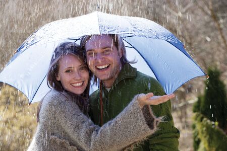 Young couple enjoying the rain under an umbrellaの写真素材