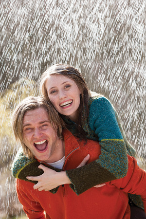 Young couple playing in the rain without an umbrellaの写真素材