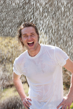 An attractive young man having fun in the rain without an umbrellaの写真素材