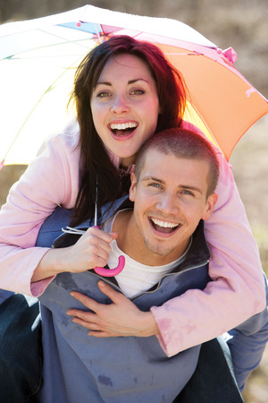 Young couple laughing in the rain under an umbrellaの写真素材