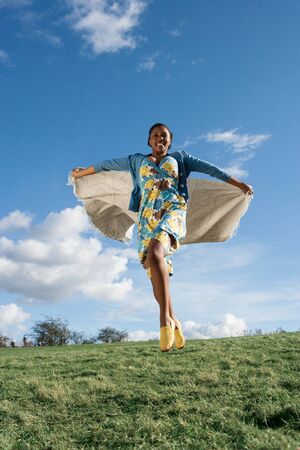 young woman running with a blanket behind herの写真素材