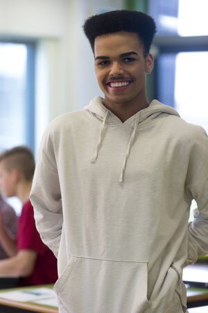 Portrait of a teenage boy in his school classroom. he is smiling and looking at the camera.