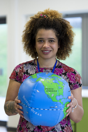 Teacher in a classroom holding a blow up globe to the camera.