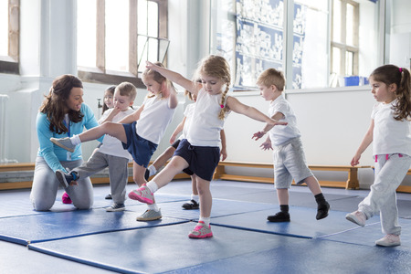 Nursery teacher helping one of her students during a physical education lesson.の写真素材