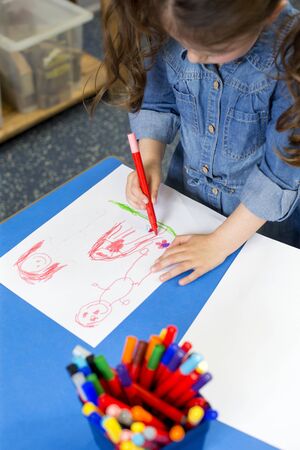 Little girl drawing a picture in nursery with felt tip pens.の写真素材