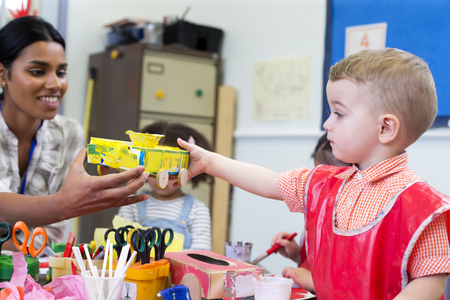 Little boy in nursery showing his teacher the cereal box car he has made.の写真素材