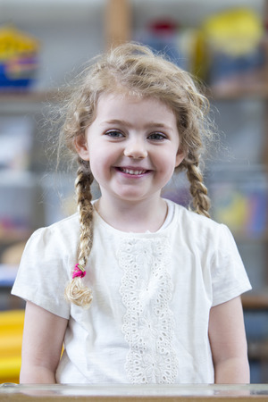 Portrait of a school girl. She is wearing a white top and smiling at the camera.の写真素材
