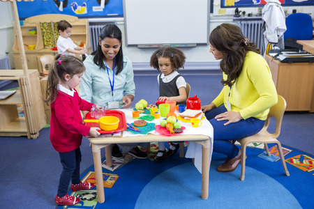 Teachers playing with plastic kitchen toys with their nursery students in the classroom.の写真素材