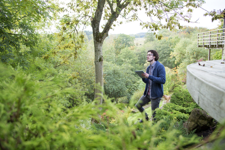 Young man using a digital tablet to analyse trees.の写真素材