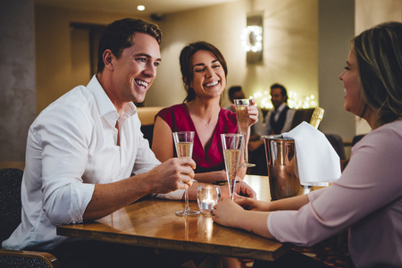 Group of friends enjoying a bottle of champagne in a restaurant.の写真素材