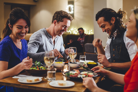Group of friends enjoying an evening meal with wine at a restaurant.の写真素材