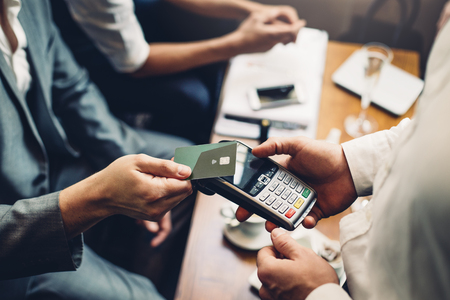 Close up of a card payment being made betweem a man and a waiter in a cafe.の写真素材