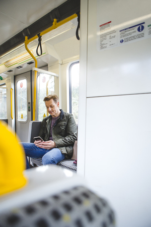 Man sitting on the train using his smart phone.の写真素材