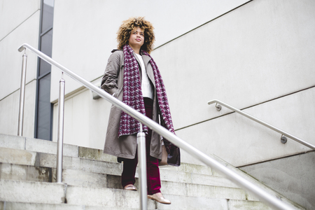 Businesswoman commuting to work in the city. She is walking down some stairs.の写真素材